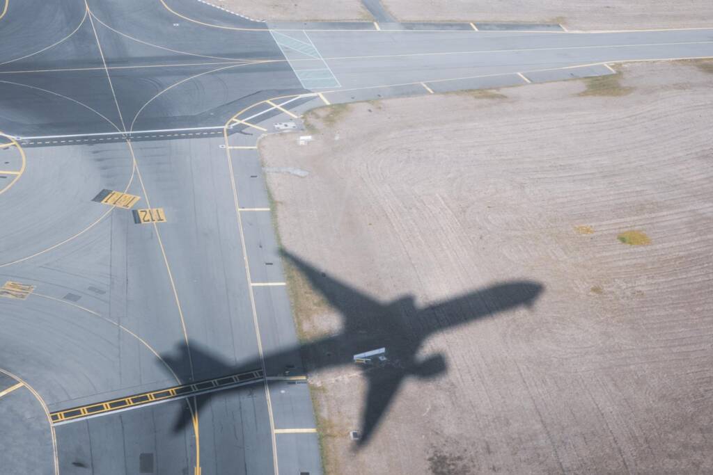 Shadow of airplane taking off over airport runway